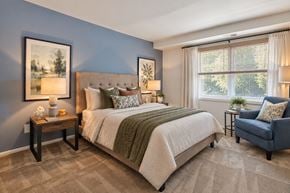 Windsor Mill townhouse for rent - A bedroom with a large bed, a chair, and two framed pictures on the wall.