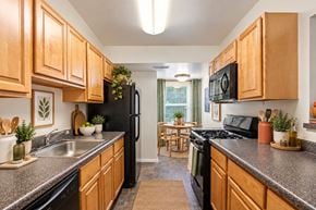 Windsor Mill townhouse for rent - A kitchen with wooden cabinets and black appliances.