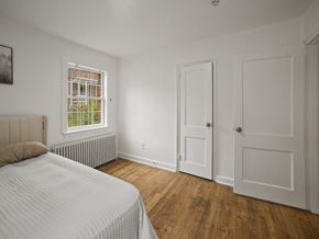 Washington apartment for rent - A bedroom with a bed, wooden floors, and a window with blinds.