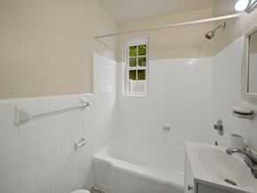 Washington apartment for rent - A white bathroom with a tub, sink, and toilet.