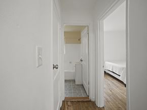 Washington apartment for rent - A white hallway with a door on the left and a bed on the right.