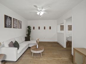Washington apartment for rent - A living room with a white couch, a wooden coffee table, and a ceiling fan.