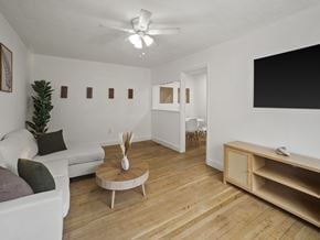 Washington apartment for rent - A living room with a white couch, a wooden coffee table, and a TV on the wall.