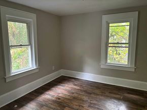 Akron house for rent - A room with two windows and wooden flooring.