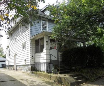 Akron house for rent - A two-story house with a porch and a tree in front.