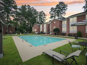 Fayetteville apartment for rent - A pool surrounded by lawn chairs and trees.