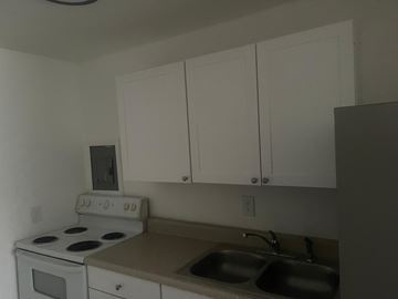 Vero Beach apartment for rent - A kitchen with white cabinets and a white stove top oven.