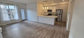 Calgary house for rent - an empty living room with a kitchen and a large window