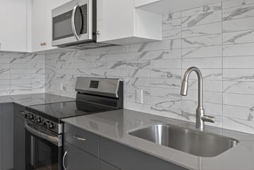 Kelowna apartment for rent - A modern kitchen with a stainless steel sink and a microwave above the stove.