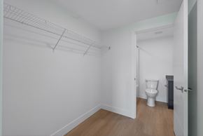 Kelowna apartment for rent - A white toilet sits in a small room with a white wall and a door.
