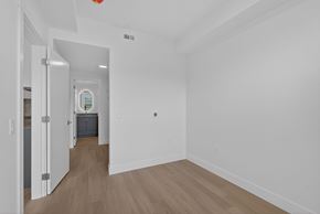 Kelowna apartment for rent - A room with white walls and wooden flooring with a doorway leading to another room.