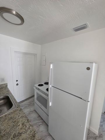 Vero Beach apartment for rent - A white fridge and oven in a kitchen with a sink.