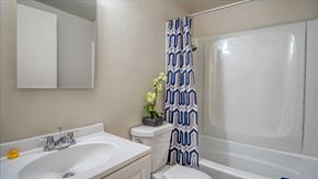 Spokane Valley apartment for rent - A white sink with a yellow soap and a blue and white shower curtain.