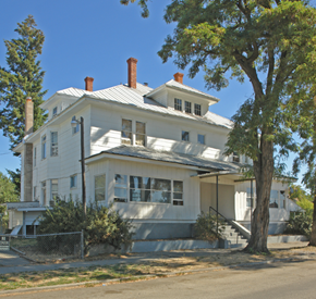 Spokane apartment for rent - A white house with a grey roof and a tree in front.