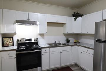 Spokane apartment for rent - A kitchen with white cabinets and a black stove top oven.