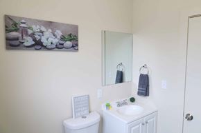 Spokane apartment for rent - A bathroom with a toilet, sink, mirror, and a painting on the wall.