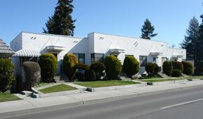 Spokane apartment for rent - A row of white houses with green bushes in front.