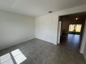 Miami Shores house for rent - an empty living room with tile floor and white walls