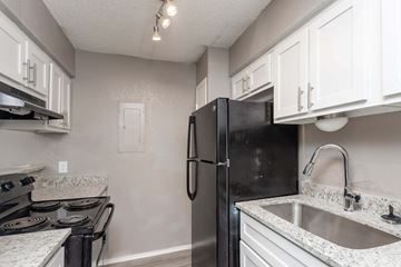 Fort Worth apartment for rent - a kitchen with white cabinets and a black refrigerator