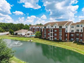 Greenwood apartment for rent - a fountain in a pond in front of an apartment building