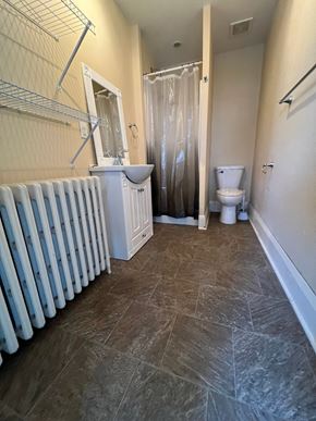 Grinnell apartment for rent - A bathroom with a white radiator, toilet, and sink.