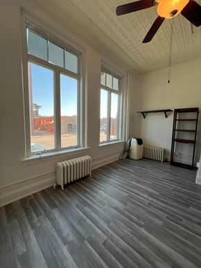Grinnell apartment for rent - A room with a ceiling fan and a window overlooking a parking lot.