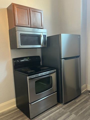Grinnell apartment for rent - A kitchen with a black stove and oven, a microwave above it, and a silver refrigerator to the right.