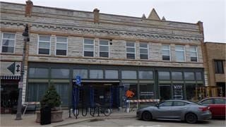 Grinnell apartment for rent - A grey car is parked in front of a building with a blue sign.