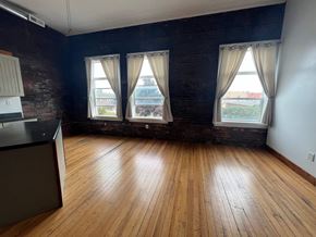 Grinnell apartment for rent - A room with wooden floors and three windows.