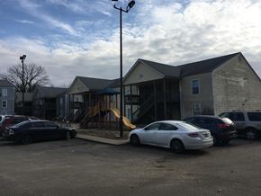 Louisville apartment for rent - A white car is parked in a lot with other cars and a playground is in the background.
