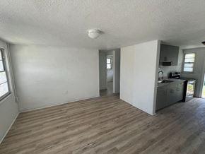 Palmetto apartment for rent - A room with wooden flooring and a kitchen area in the background.