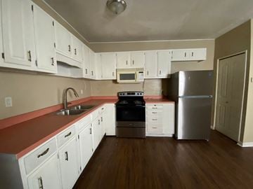 Louisville house for rent - A kitchen with white cabinets and a red counter.