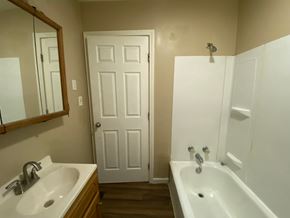 Louisville house for rent - A white bathroom with a sink, mirror, and bathtub.