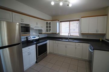 Edmonton house for rent - a kitchen with white cabinets and black counter tops