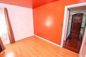 Victoria apartment for rent - an empty room with an orange wall and wooden floors