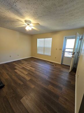 Morehead house for rent - an empty living room with a hard wood floor and a door