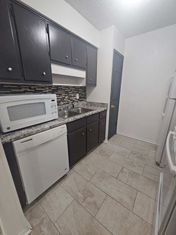 Pensacola house for rent - a kitchen with white appliances and black cabinets