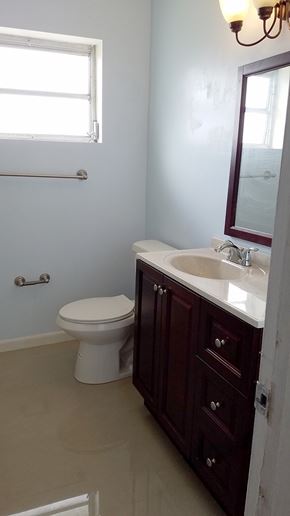 Hallandale apartment for rent - A white toilet sits in a bathroom with a brown vanity.