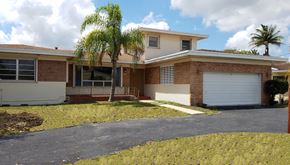 Hallandale apartment for rent - A house with a driveway and a palm tree in front.