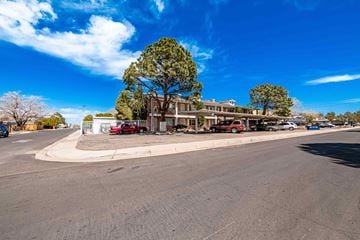 Albuquerque apartment for rent - A street view with cars, trees, and a building.