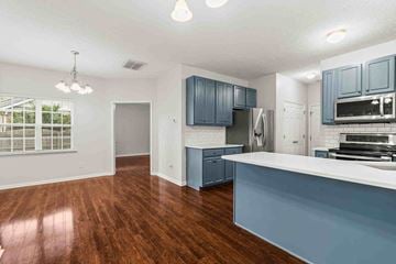 Fuquay-Varina house for rent - an open kitchen and living room with blue cabinets and a counter top