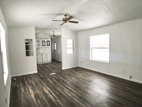 Manvel house for rent - an empty living room with wooden floors and a ceiling fan