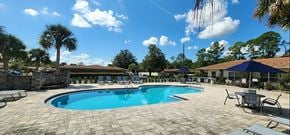 Jacksonville apartment for rent - a resort style pool with chairs around it and trees