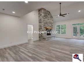 Loudon house for rent - A spacious room with a stone fireplace and Key Properties LLC logo.