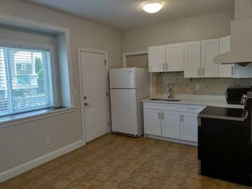 Burnaby house for rent - a kitchen with white cabinets and a white refrigerator