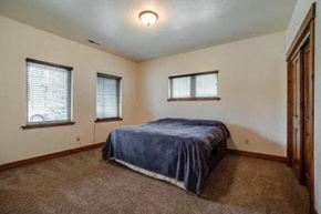 Whitefish house for rent - a bedroom with a bed and three windows