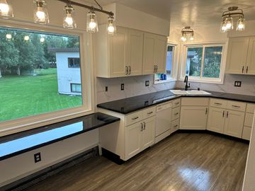 Anchorage apartment for rent - A kitchen with white cabinets and a black countertop.