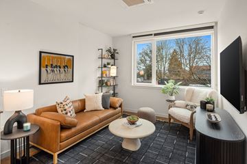 Seattle apartment for rent - A living room with a brown couch, a white coffee table, and a painting on the wall.