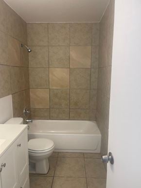 Fort Myers apartment for rent - A white toilet sits next to a white bathtub in a tiled bathroom.