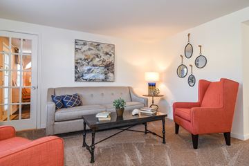 Severn apartment for rent - A living room with a grey couch, a red chair, a black coffee table, and a painting on the wall.